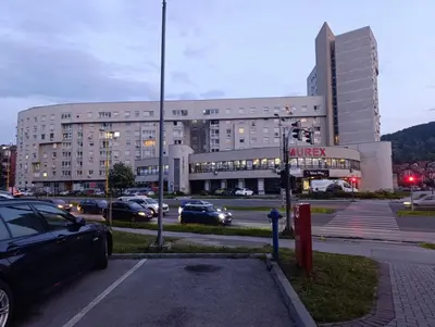 a large building with cars parked in a parking lot at Apartment Paradise in Tuzla