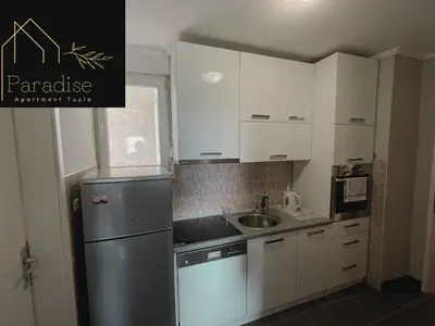 a kitchen with white cabinets and a stainless steel refrigerator at Apartment Paradise in Tuzla
