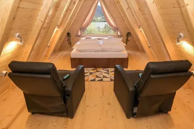 a bedroom with a bed and two chairs in a room at Cottages Relax in Jajce