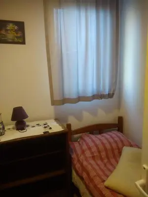 a bedroom with a bed and a dresser and a window at Hostel Mlinar in Bihać