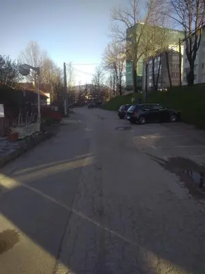 an empty street with cars parked in a parking lot at Hostel Mlinar in Bihać