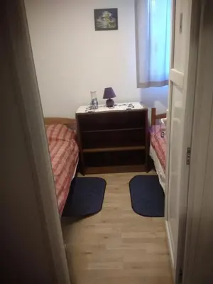 a bedroom with two beds and a table and a lamp at Hostel Mlinar in Bihać