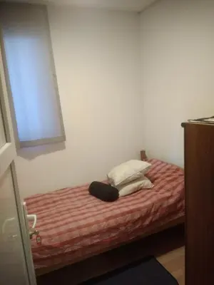 a bedroom with a bed with a red and white blanket at Hostel Mlinar in Bihać