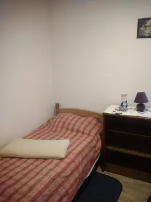 a small bedroom with a bed and a dresser at Hostel Mlinar in Bihać