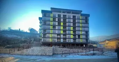 a large apartment building with yellow windows and snow at Apartman M&M in Travnik