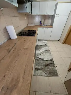 a kitchen with white cabinets and a wooden floor at Index Apartman in Banja Luka