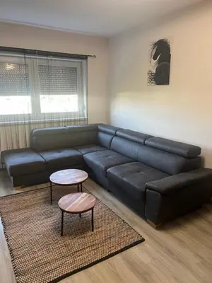 a living room with a black leather couch and a table at Una-No1 in Bihać