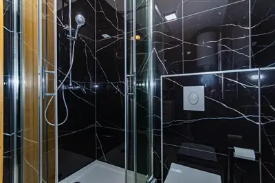a bathroom with a shower with black tiles at Apartman Krželj A2 in Livno