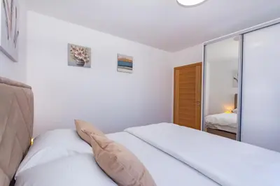 a bedroom with a white bed and a mirror at Apartman Krželj A2 in Livno