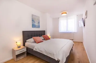 a bedroom with a bed with white sheets and orange pillows at Apartman Krželj A3 in Livno