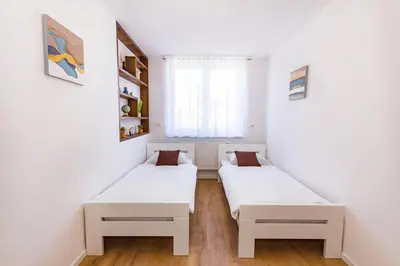 two beds in a small room with a window at Apartman Krželj A3 in Livno