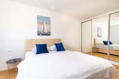a bedroom with a large white bed with blue pillows at Apartman Krželj A4 in Livno
