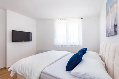 a white bedroom with a bed with blue pillows at Apartman Krželj A4 in Livno
