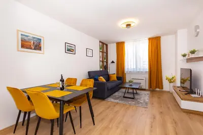 a living room with a table and yellow chairs at Apartman Krželj A4 in Livno