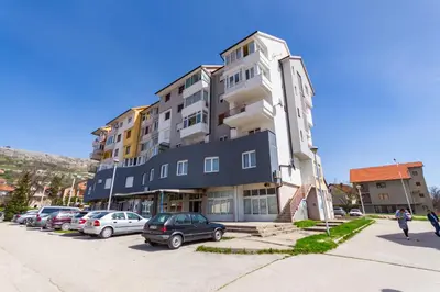 a large building with cars parked in a parking lot at Apartman Krželj A4 in Livno