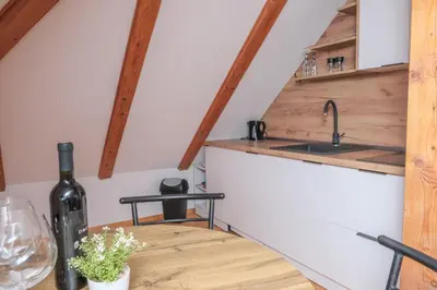 a kitchen with a wooden table with a bottle of wine at Apartman Maja in Jajce