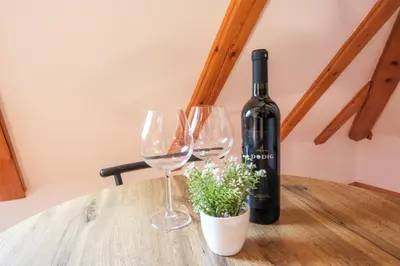 a bottle of wine and two wine glasses on a table at Apartman Maja in Jajce