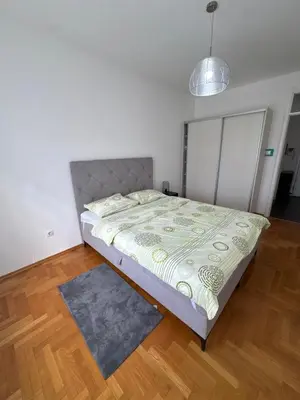 a bedroom with a bed in a room with wooden floors at Apartman 50 in Banja Luka