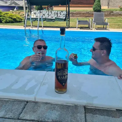 two men in a swimming pool with a bottle of beer at Villa Mia in Prnjavor