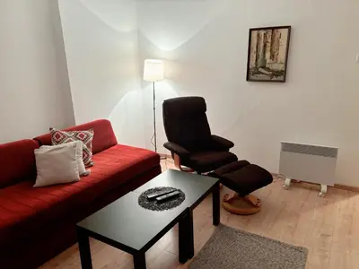 a living room with a red couch and a chair at Stan na dan CentarM in Banja Luka