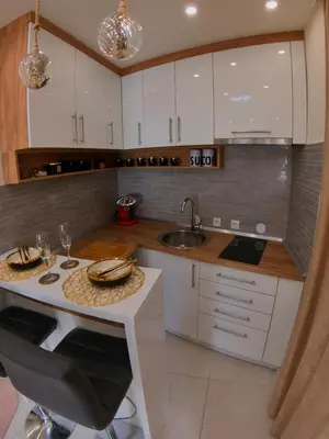 a kitchen with white cabinets and a sink and a table at Stan na dan sa dzakuzijem om relax in Prijedor