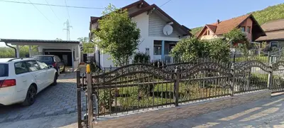 a fence in front of a white car parked in front of a house at Apartment Deluxe Holiday in Bihać