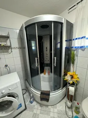 a shower in a bathroom with a washing machine at Apartment Deluxe Holiday in Bihać