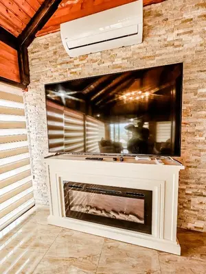 a fireplace with a tv on a brick wall at Lux Villa Emina in Tuzla