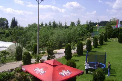 a red umbrella in a park with people on a trampoline at Resort Čokori in Banja Luka