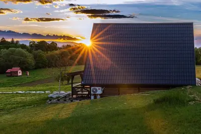 a house on a hill with the sun setting behind it at Village house Iva in Livno