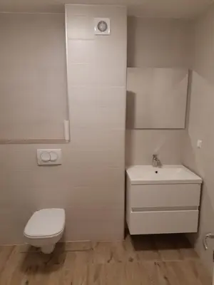 a white bathroom with a toilet and a sink at Apartman River in Prijedor
