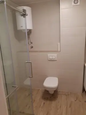 a bathroom with a toilet and a glass shower door at Apartman River in Prijedor