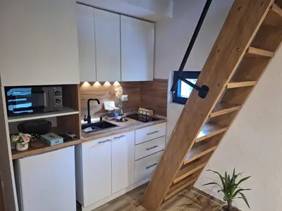 a kitchen with white cabinets and a staircase at Oaza mira 1 in Jajce