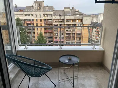 a balcony with a chair and a table and a window at Alex apartment in Banja Luka