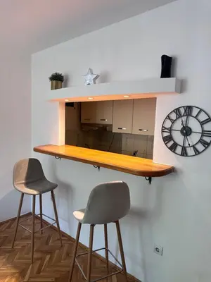 a counter with two stools and a clock on a wall at Central13 App 3 in Tuzla