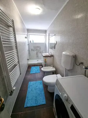a bathroom with two toilets and two blue rugs at Bell Apartment in Bihać
