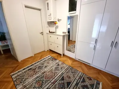 a room with a rug on a wooden floor and a white door at Bell Apartment in Bihać