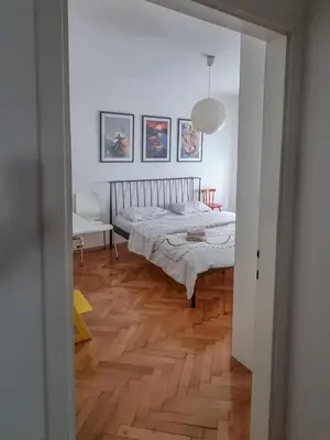 a bedroom with a bed and a wooden floor at Bell Apartment in Bihać