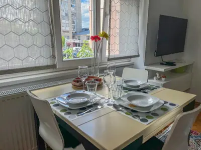a dining room table with plates and glasses on it at Bell Apartment in Bihać