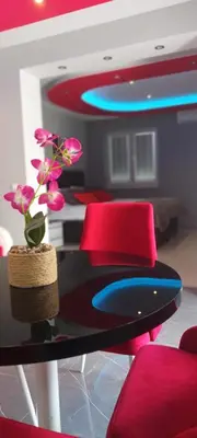 a table with red chairs and a vase with flowers on it at Apartment Deluxe Livno in Livno