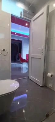 a bathroom with a door open to a room with a red chair at Apartment Deluxe Livno in Livno