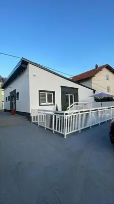 a white building with a white fence in a parking lot at Apartment Deluxe Livno in Livno