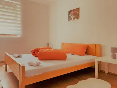 a bed with orange pillows on it in a room at Apartman Maric in Drvar