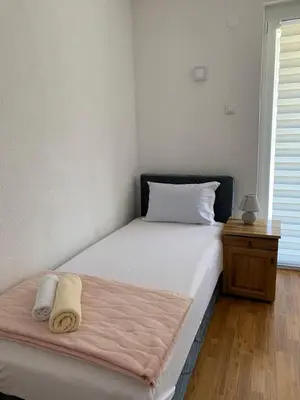 a bedroom with a white bed with a wooden floor at Apartmani CENTAR in Jajce