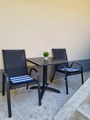 two chairs and a wooden table with a plant on it at Apartmani CENTAR in Jajce