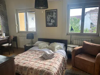 a bedroom with a bed and a chair and windows at Bolek mansion in Banja Luka