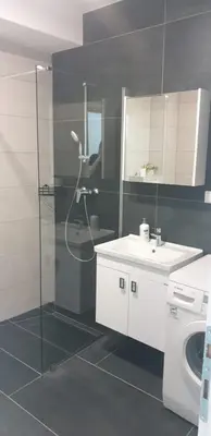 a bathroom with a shower and a sink and a washing machine at Pinocchio in Bihać