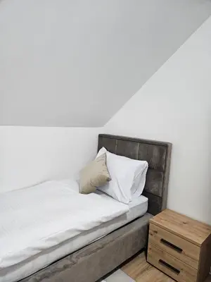 a bed with white sheets and a wooden night stand at Mrakovica 1935 in Prijedor