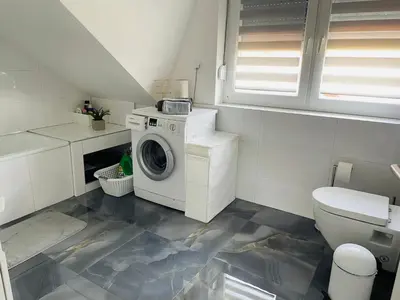 a bathroom with a washing machine and a toilet at Apartment Vuleta Deluxe Extra groß in Prijedor