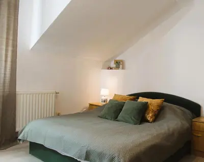 a bedroom with a bed with green and gold pillows at Svila Apartmani in Bihać